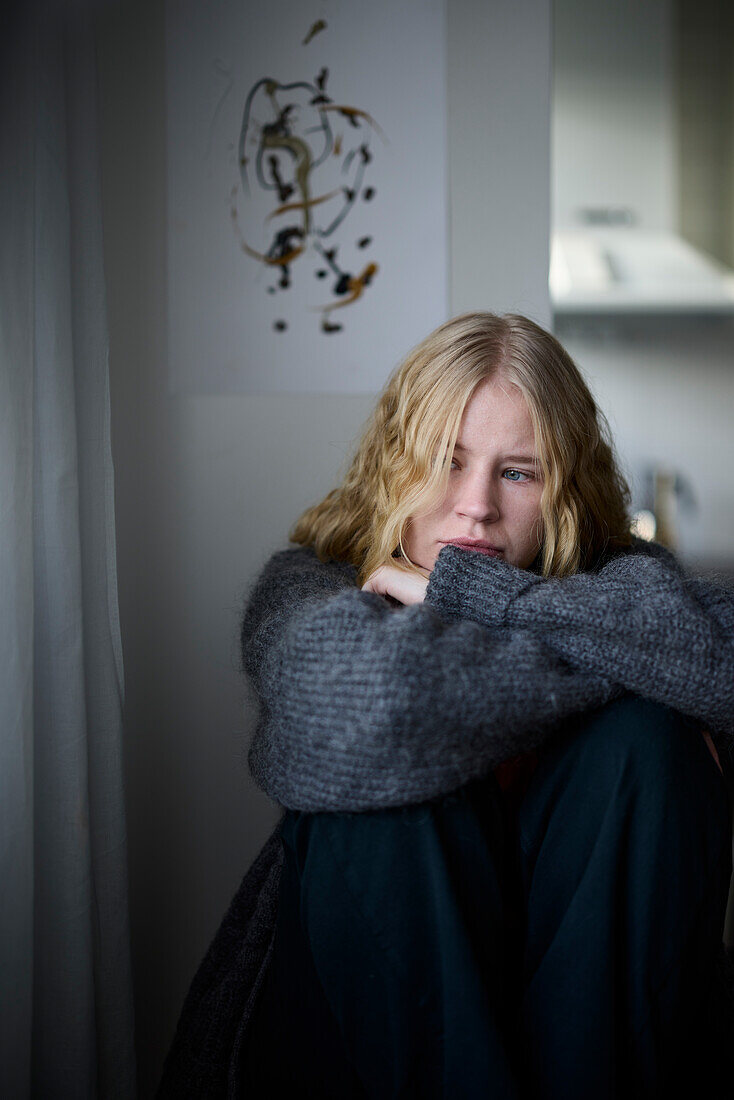 Pensive teenage girl sitting at home