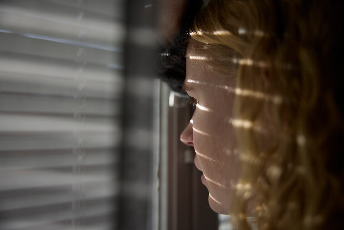 Nahaufnahme eines nachdenklichen Teenagers, der durch ein Fenster schaut