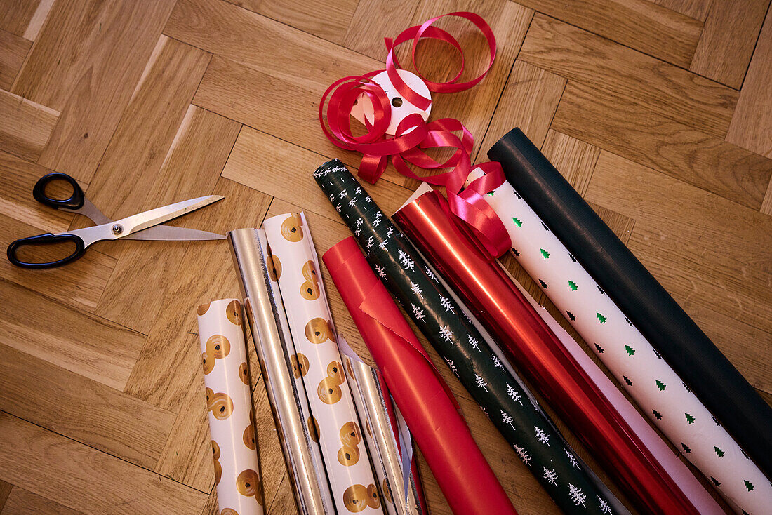 Verschiedene Weihnachtsgeschenkpapiere und Scheren auf dem Boden