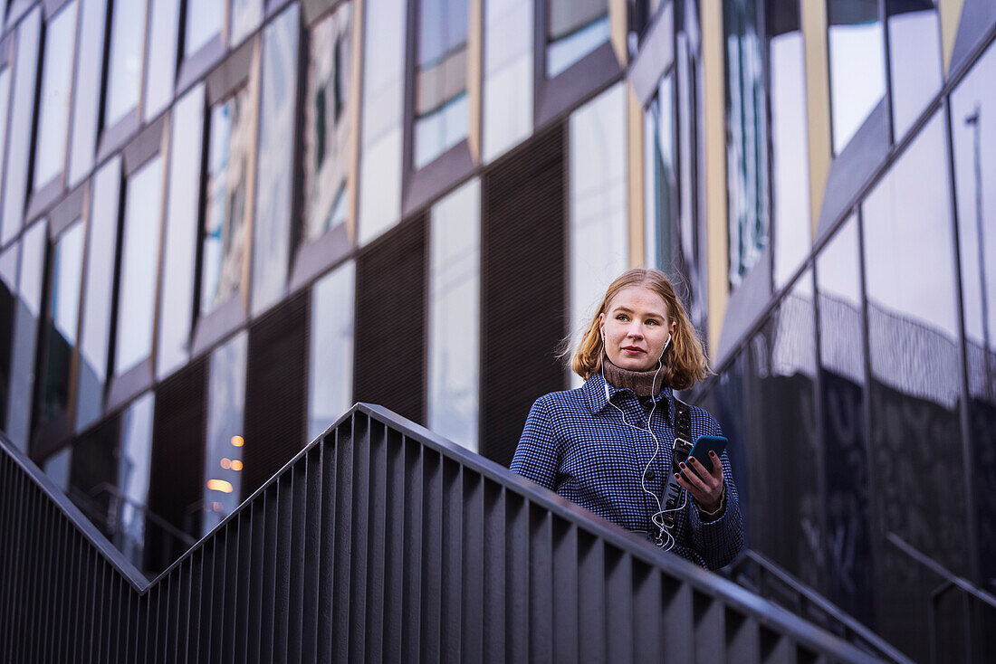 Junge Frau, die eine Treppe hinuntergeht und telefoniert