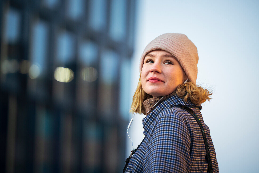 Smiling young woman wearing headphones outdoors