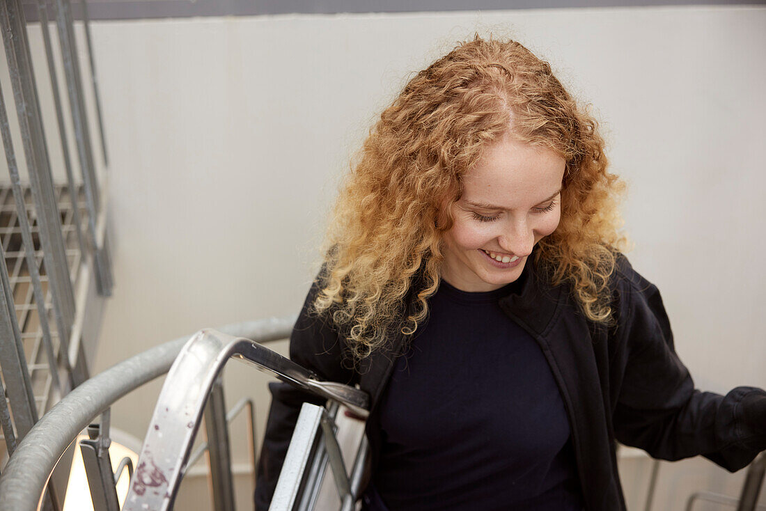 Smiling young woman carrying ladder