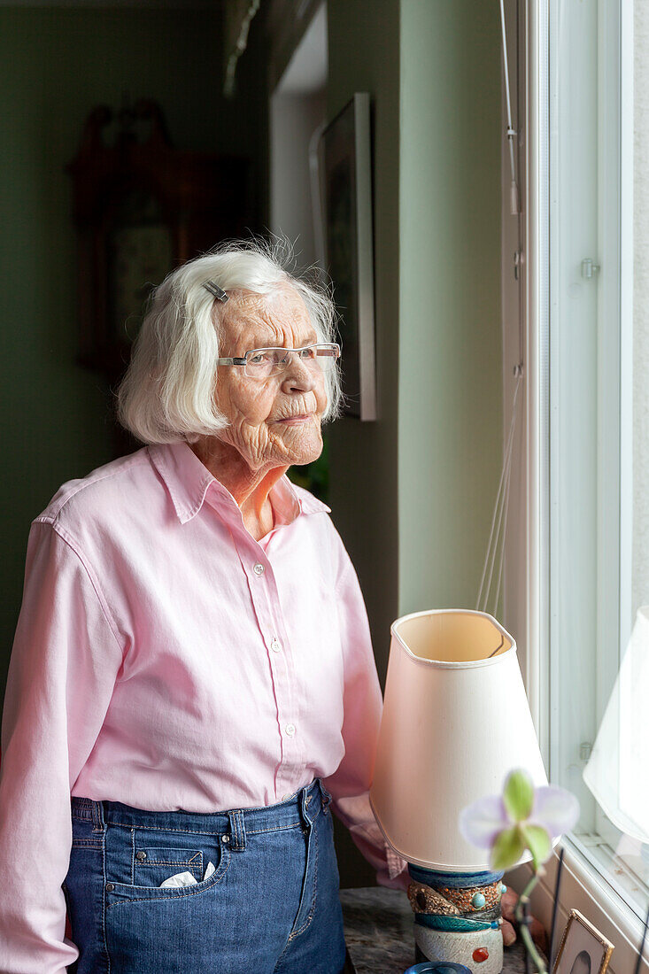 Ältere Frau blickt durch das Fenster – Bild kaufen – 13804402 ❘