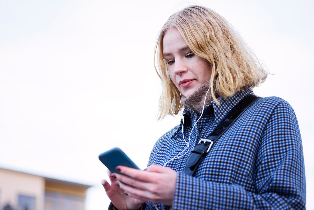 Junge Frau, die ein Mobiltelefon benutzt