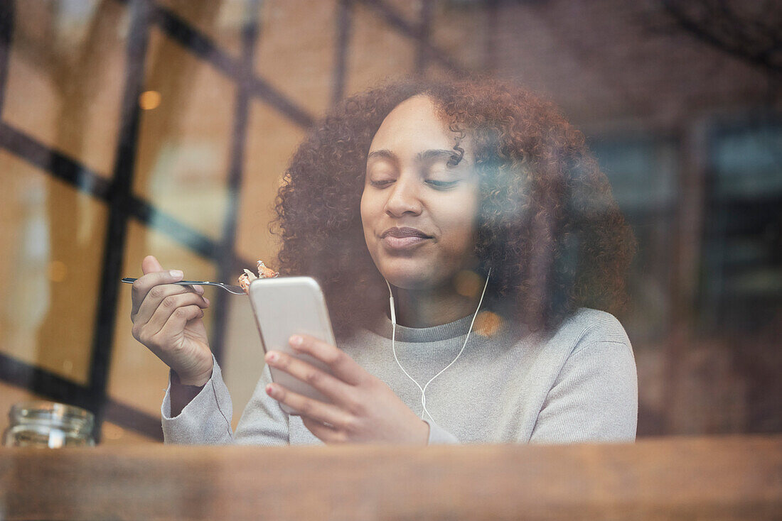 Young woman using cell phone in cafe