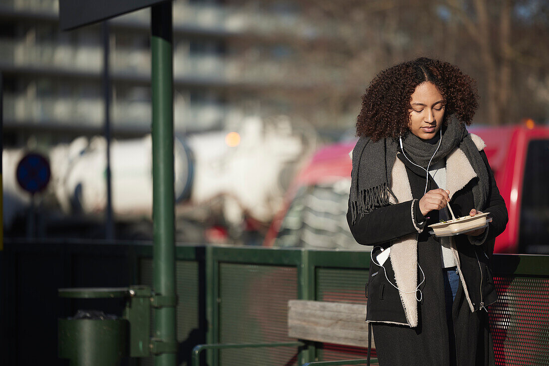 Woman eating at bus stop