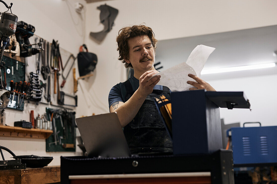 Schmied liest Dokumente in seiner Werkstatt