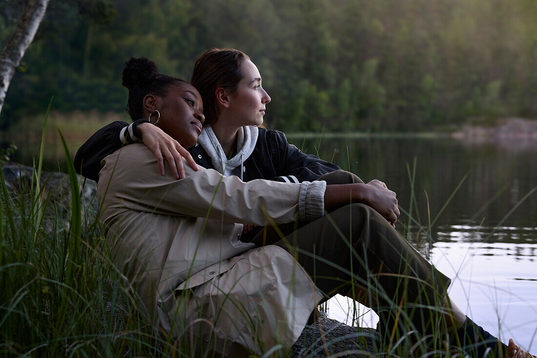 Young women sitting together at lake