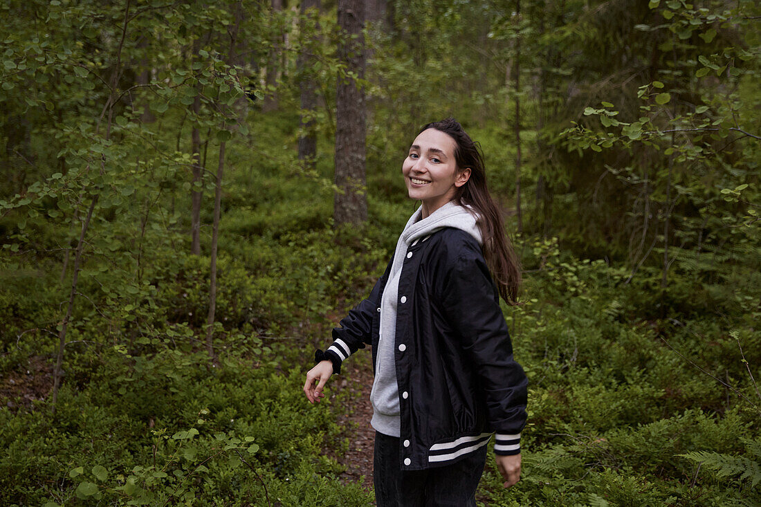 Lächelnde Frau im Wald schaut in die Kamera