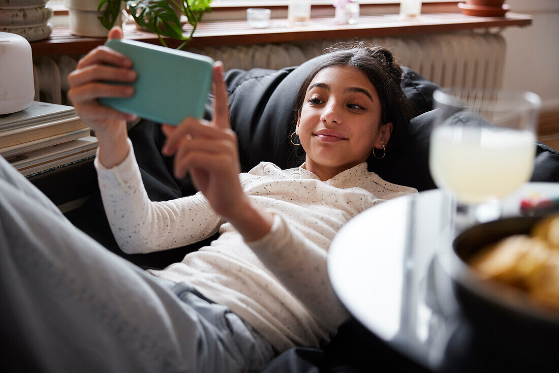 Mädchen, das auf einem Sitzsack liegt und ein Selfie macht