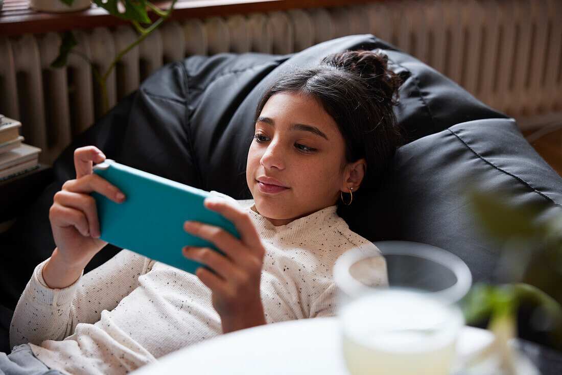 Girl lying on bean bag and playing video games