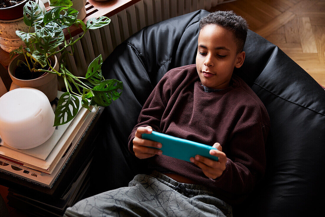 Boy lying on bean bag and playing video games