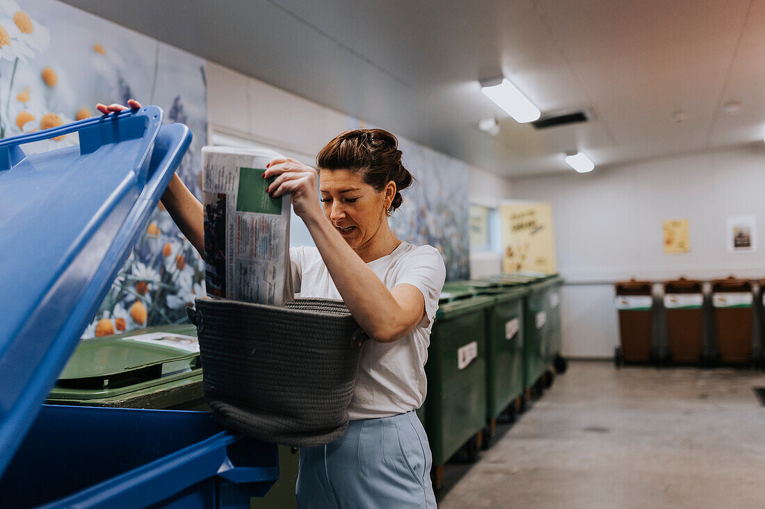 Lächelnde Frau wirft Recycling in die Mülltonne