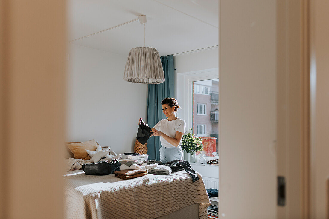 Woman folding clothes in bedroom