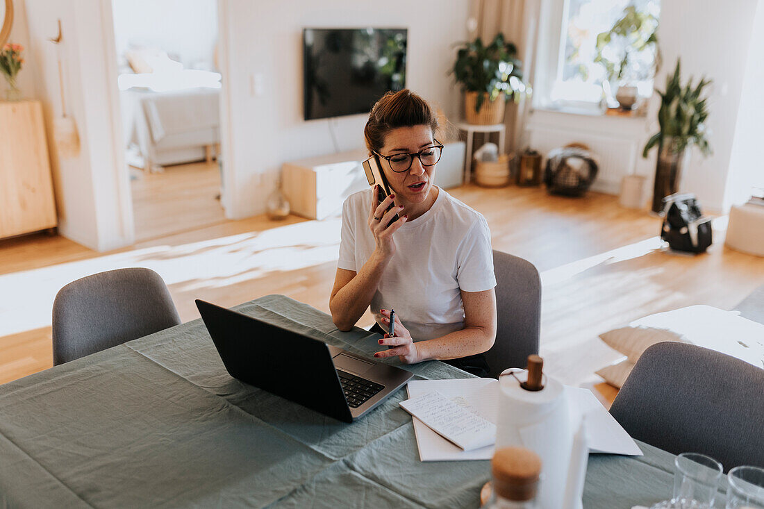 Lächelnde Frau, die zu Hause einen Laptop benutzt