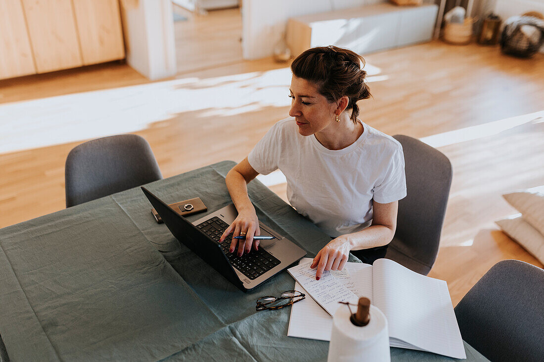 Lächelnde Frau, die zu Hause einen Laptop benutzt