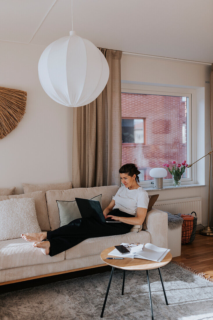 Woman using laptop on sofa