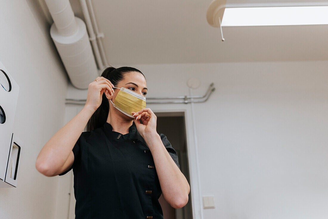 Female dentist putting protective face mask on
