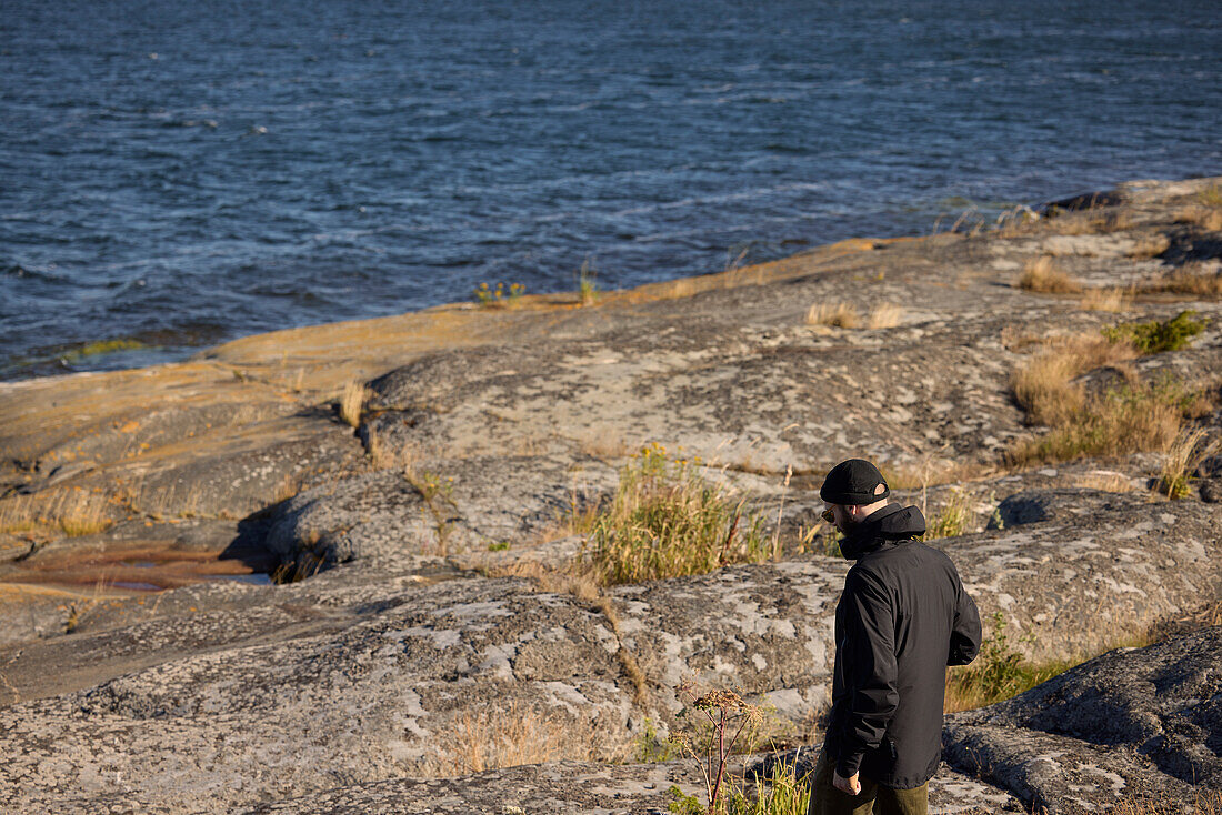Blick auf einen Mann, der an einer Felsenküste spazieren geht