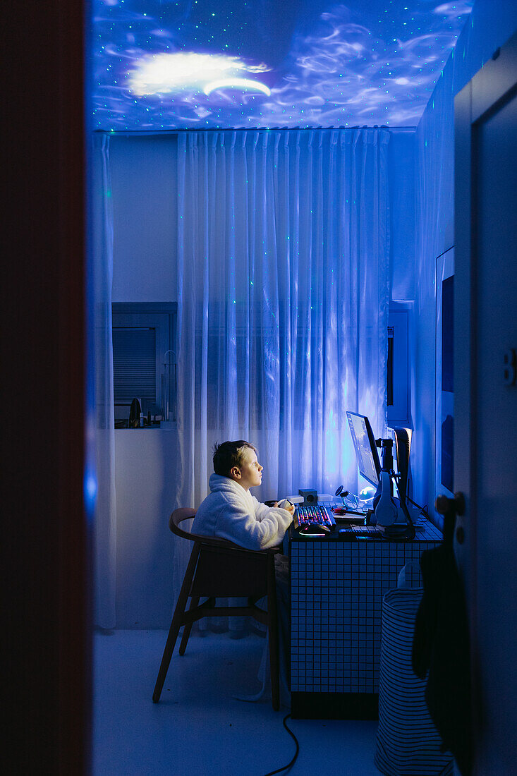 Boy at desk using computer at night