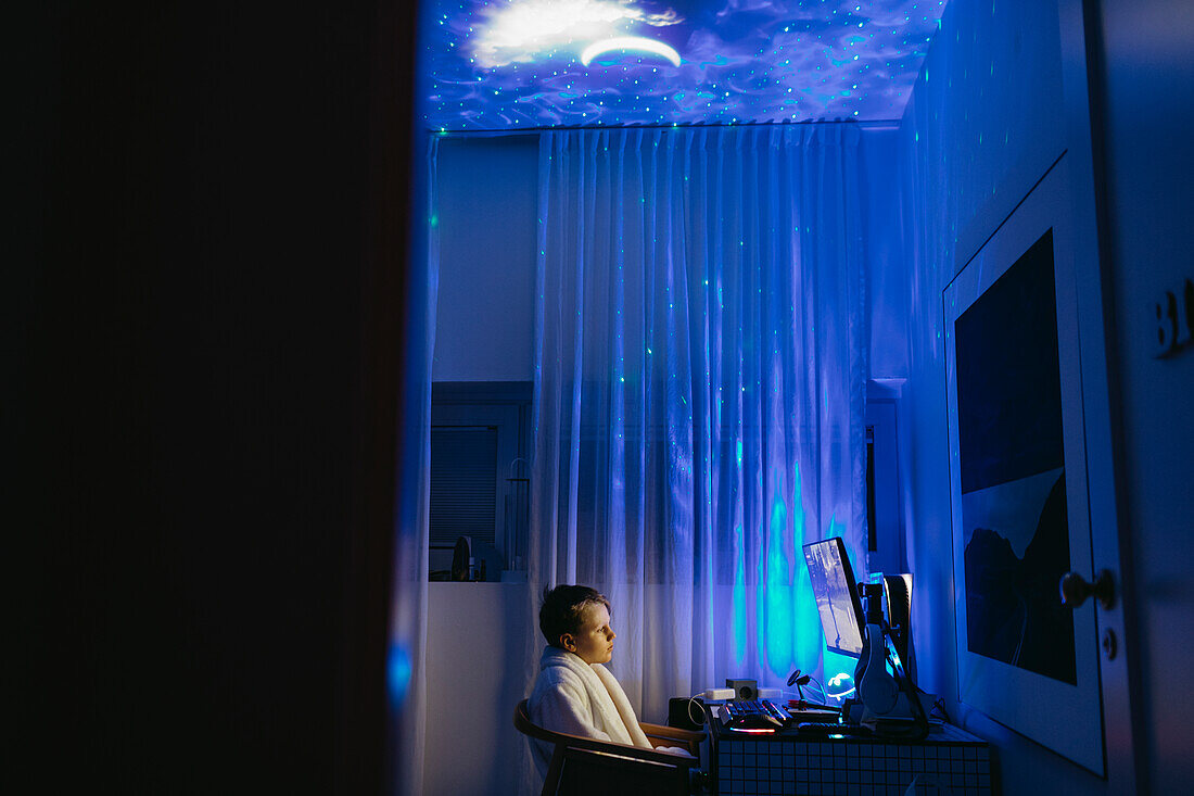 Junge am Schreibtisch, der nachts am Computer sitzt