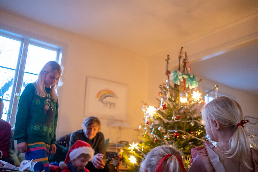 Familie beim Feiern neben dem Weihnachtsbaum