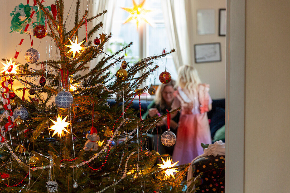 Mädchen mit Mutter beim Feiern neben dem Weihnachtsbaum