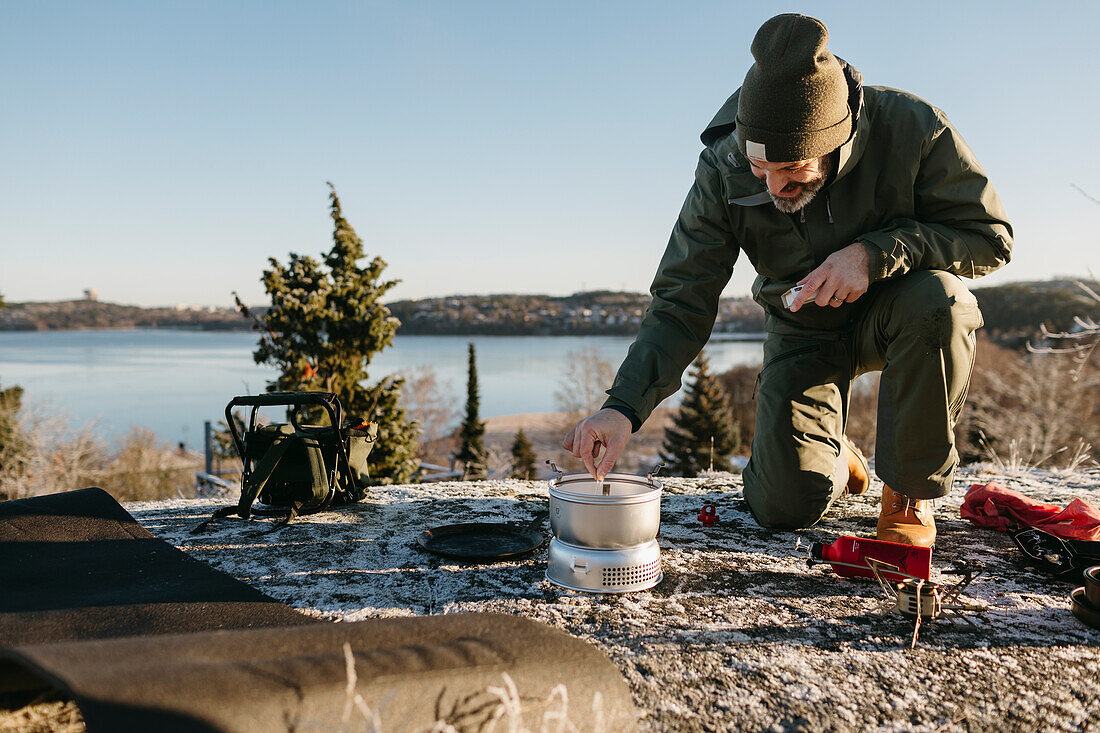 Mann bereitet im Winter Essen im Freien zu