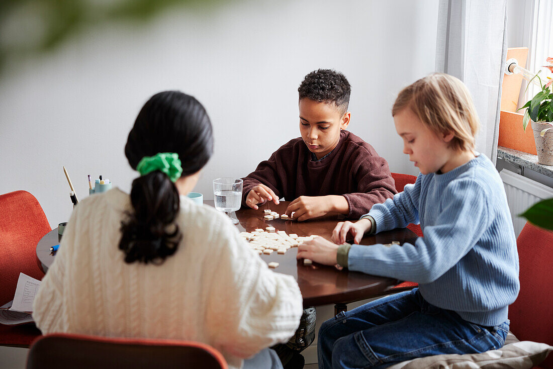 Mädchen und Jungen spielen Scrabble am Esstisch