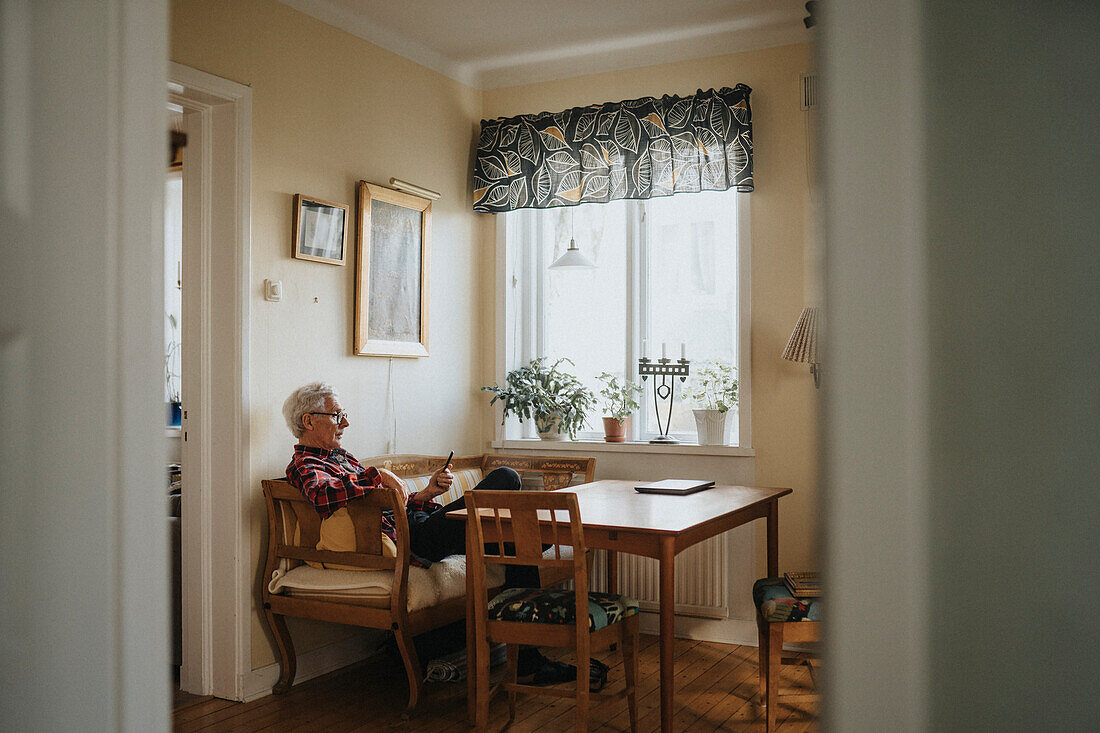 Älterer Mann benutzt sein Smartphone zu Hause