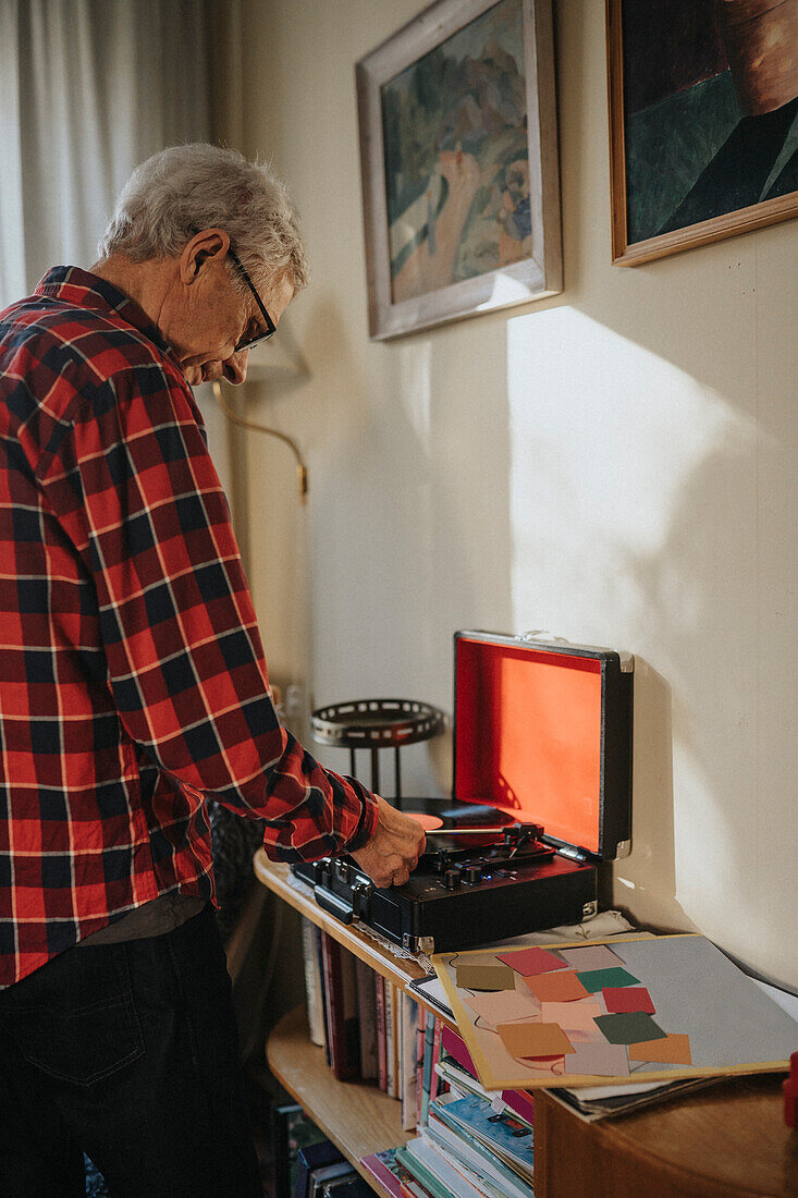 Älterer Mann benutzt zu Hause ein Grammophon