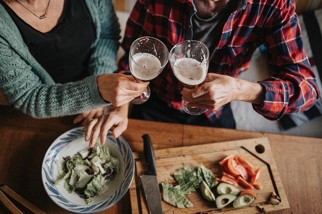 Älteres Paar trinkt Alkohol und bereitet Essen zu