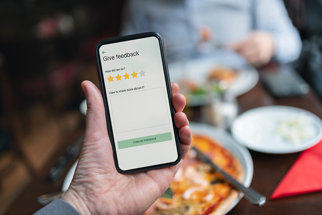 Person hält Smartphone mit Restaurantbewertungs-App