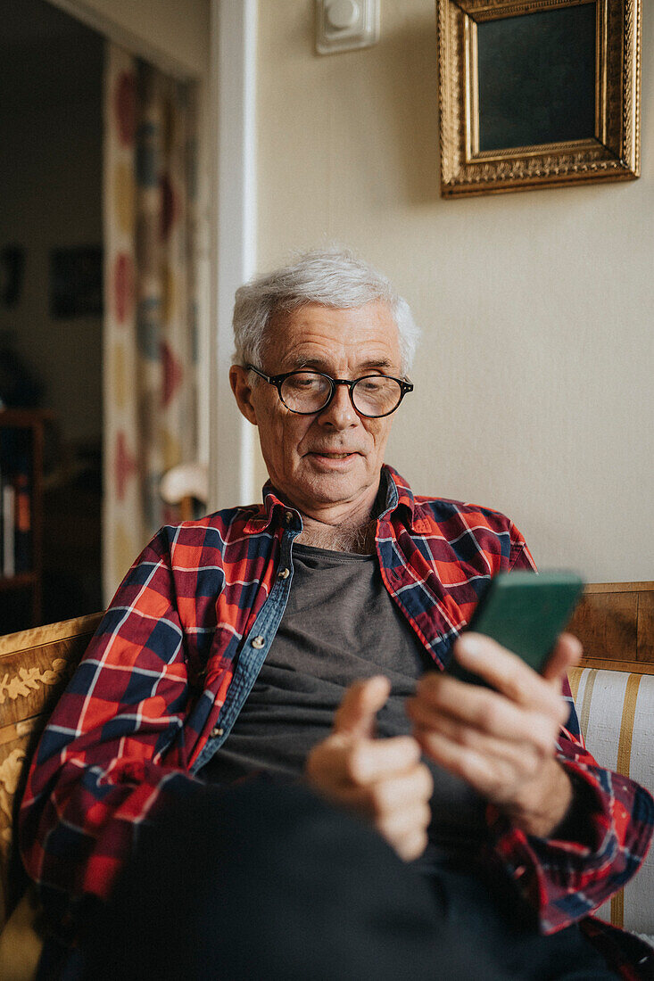 Ein älterer Mann benutzt ein Smartphone zu Hause