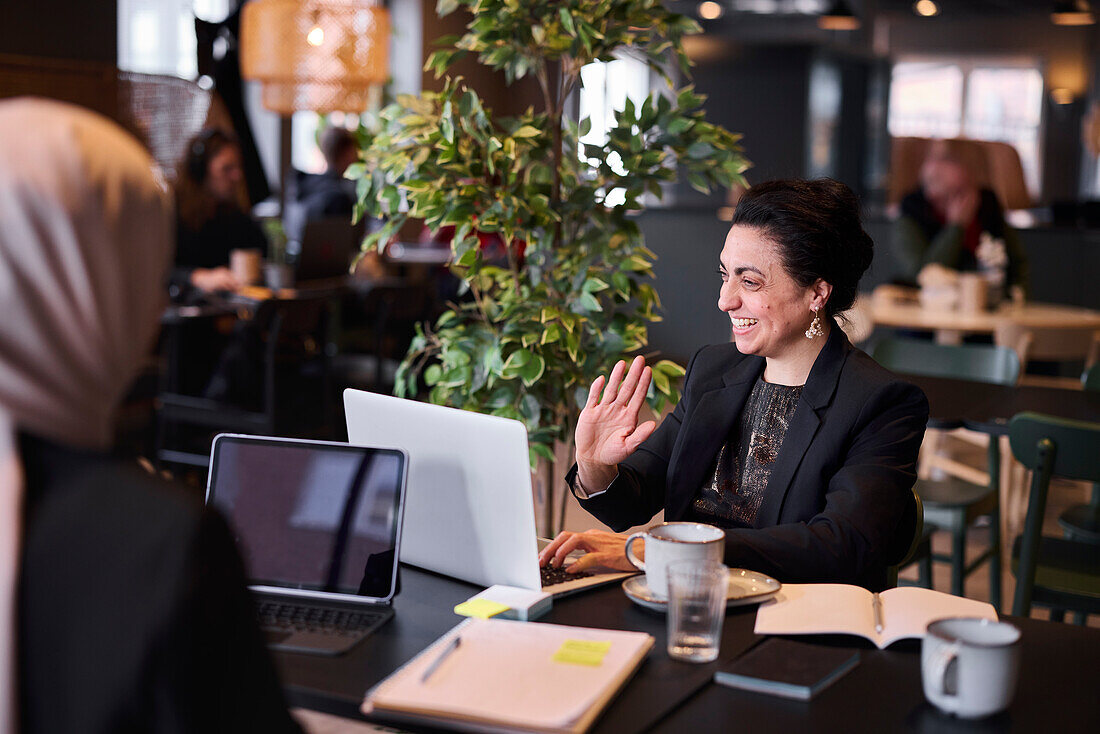 Smiling businesswoman using laptop in cafe