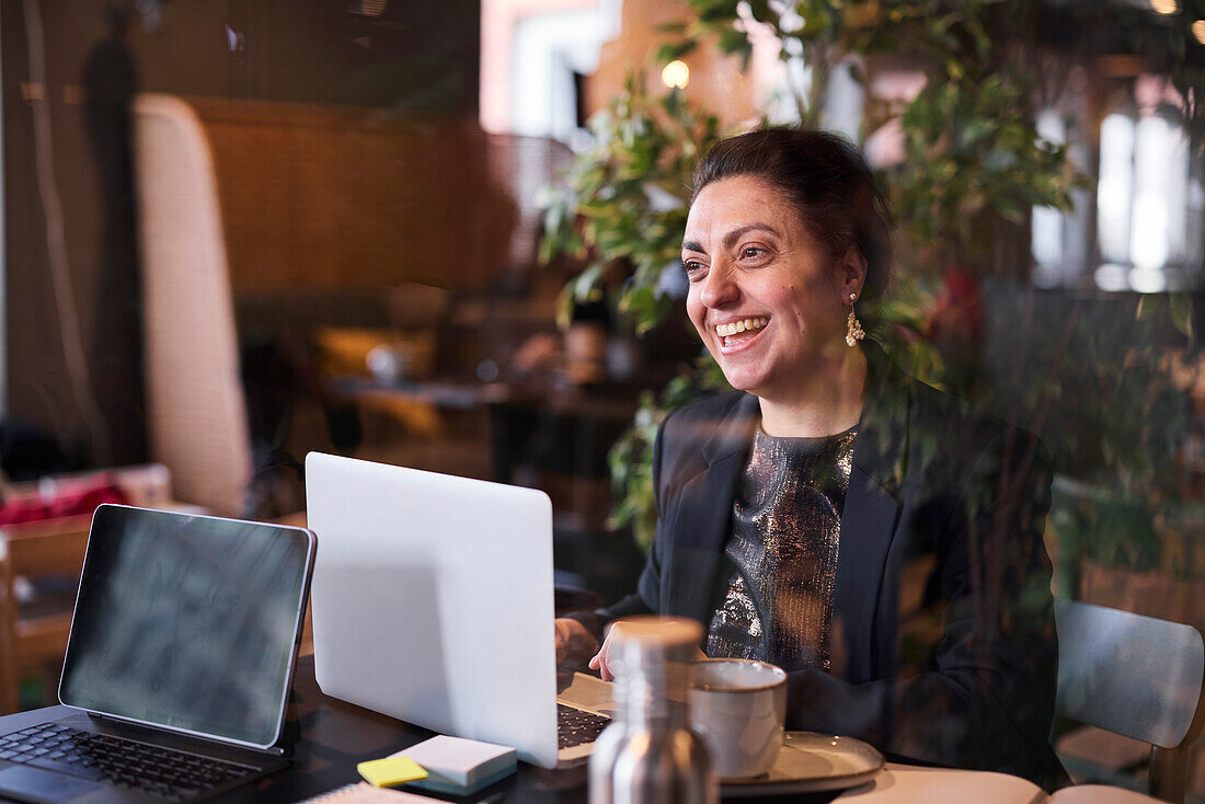 Smiling businesswoman using laptop in cafe