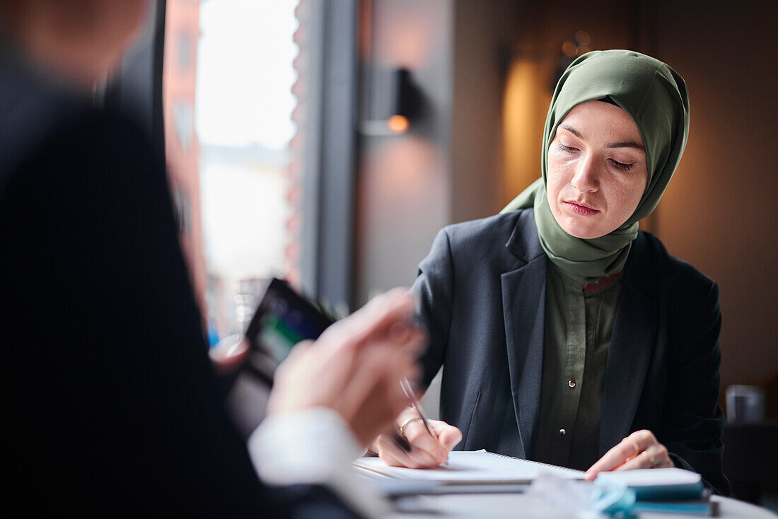 Frau mit Kopftuch im Café sitzend