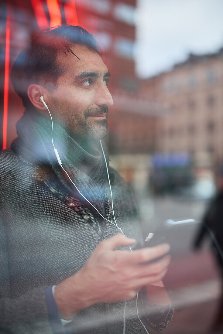 Elegant man with smartphone reflecting in window