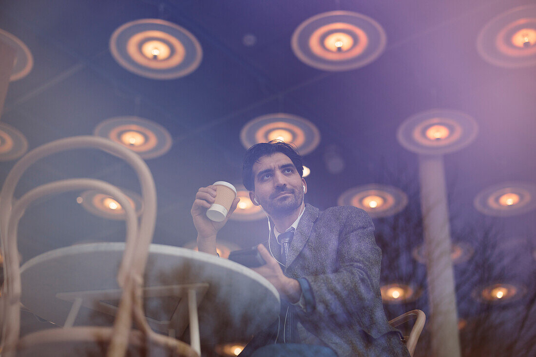 Elegant man with smartphone sitting in cafe