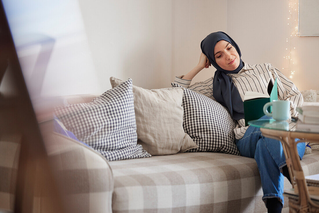 Lesende Frau auf Sofa im Wohnzimmer