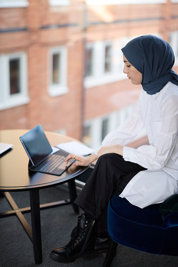 Geschäftsfrau im Hijab arbeitet mit digitalem Tablet im Büro