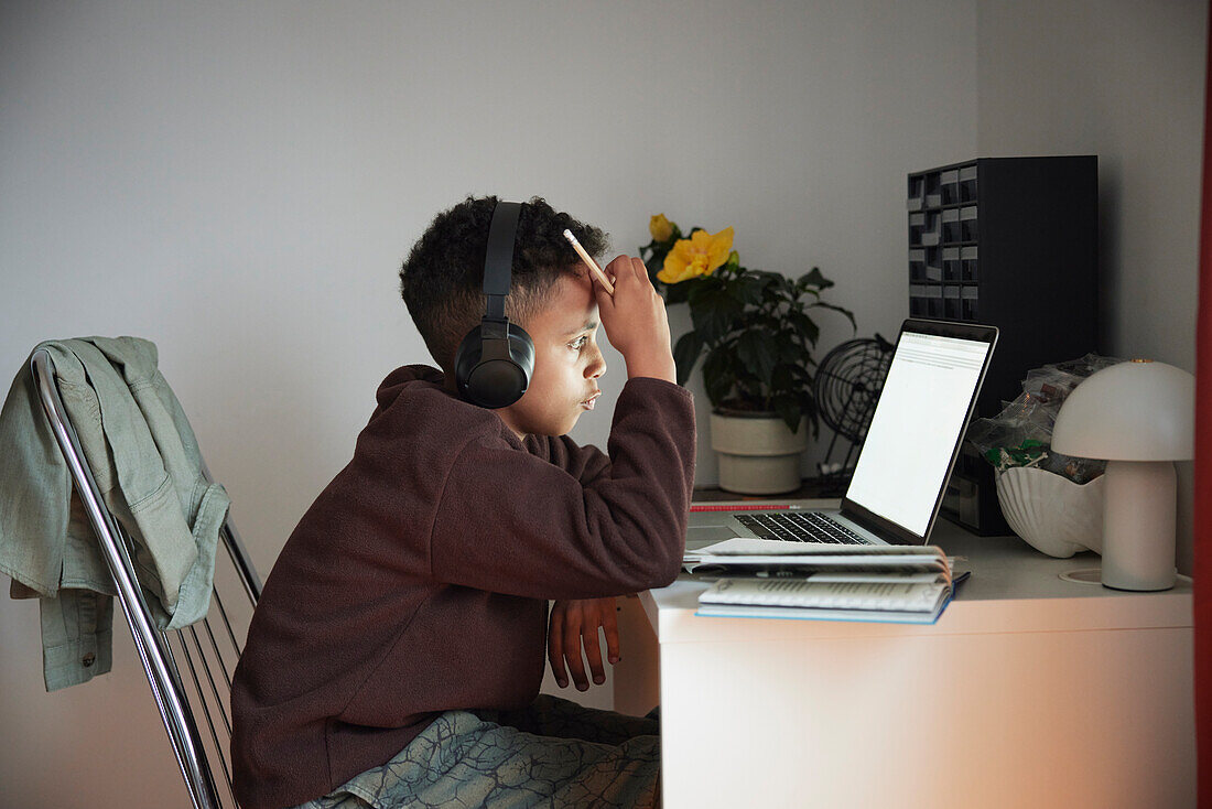 Junge macht Hausaufgaben mit Laptop
