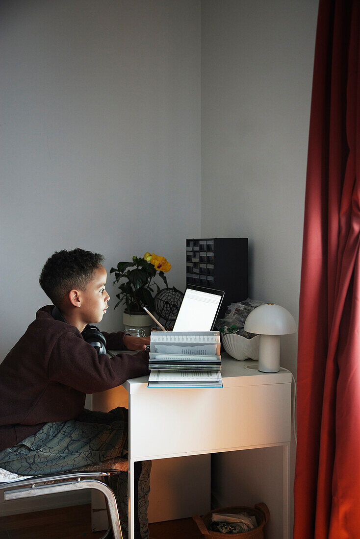 Junge macht Hausaufgaben mit Laptop