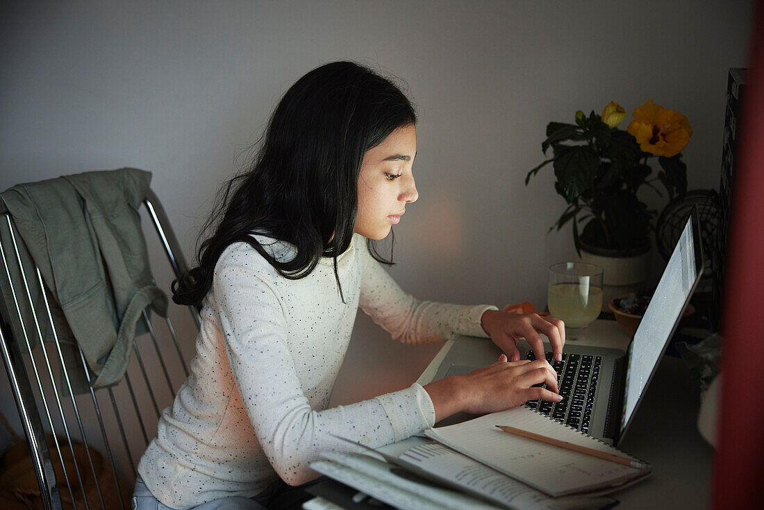 Mädchen macht Hausaufgaben mit Laptop