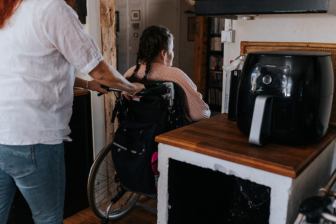 Mother pushing daughter sitting on wheelchair