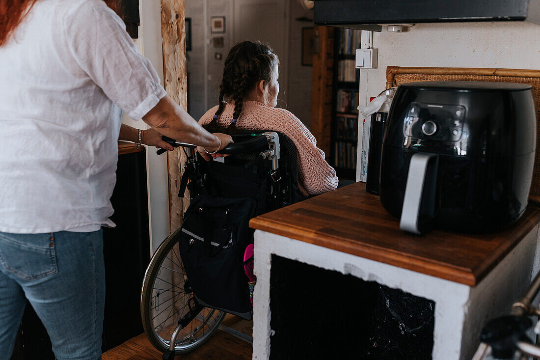 Mutter schiebt Tochter im Rollstuhl sitzend