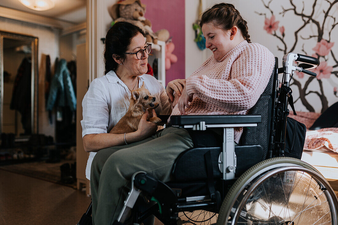 Mother with daughter on wheelchair in living room