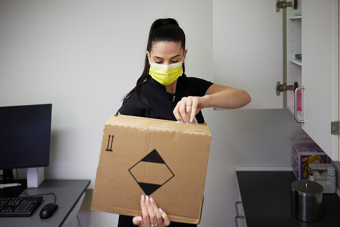 Female dentist in surgery opening cardboard box