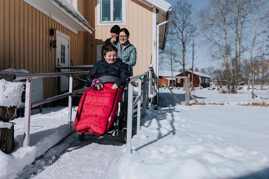Eltern machen Winterspaziergang mit Tochter im Rollstuhl
