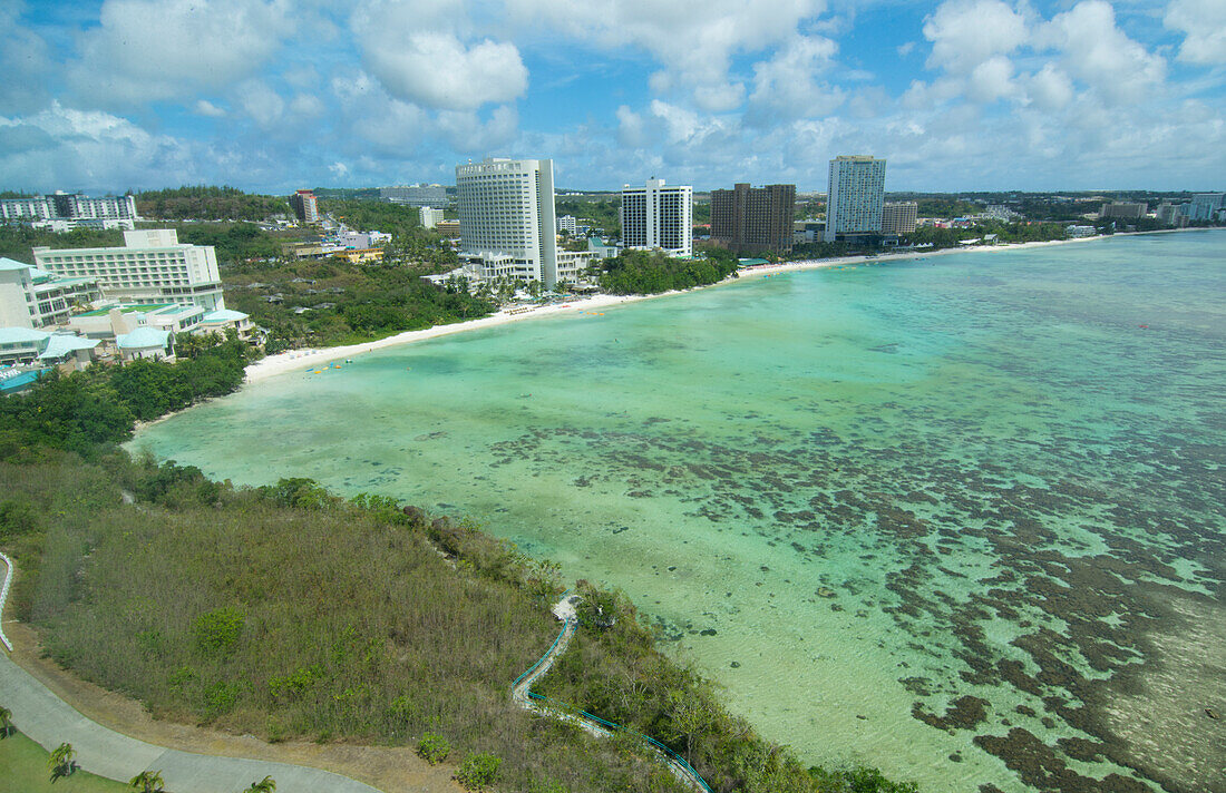 Guam, USA Territory. Tumon Bay hotels and beach from above with ocean beach and clouds
